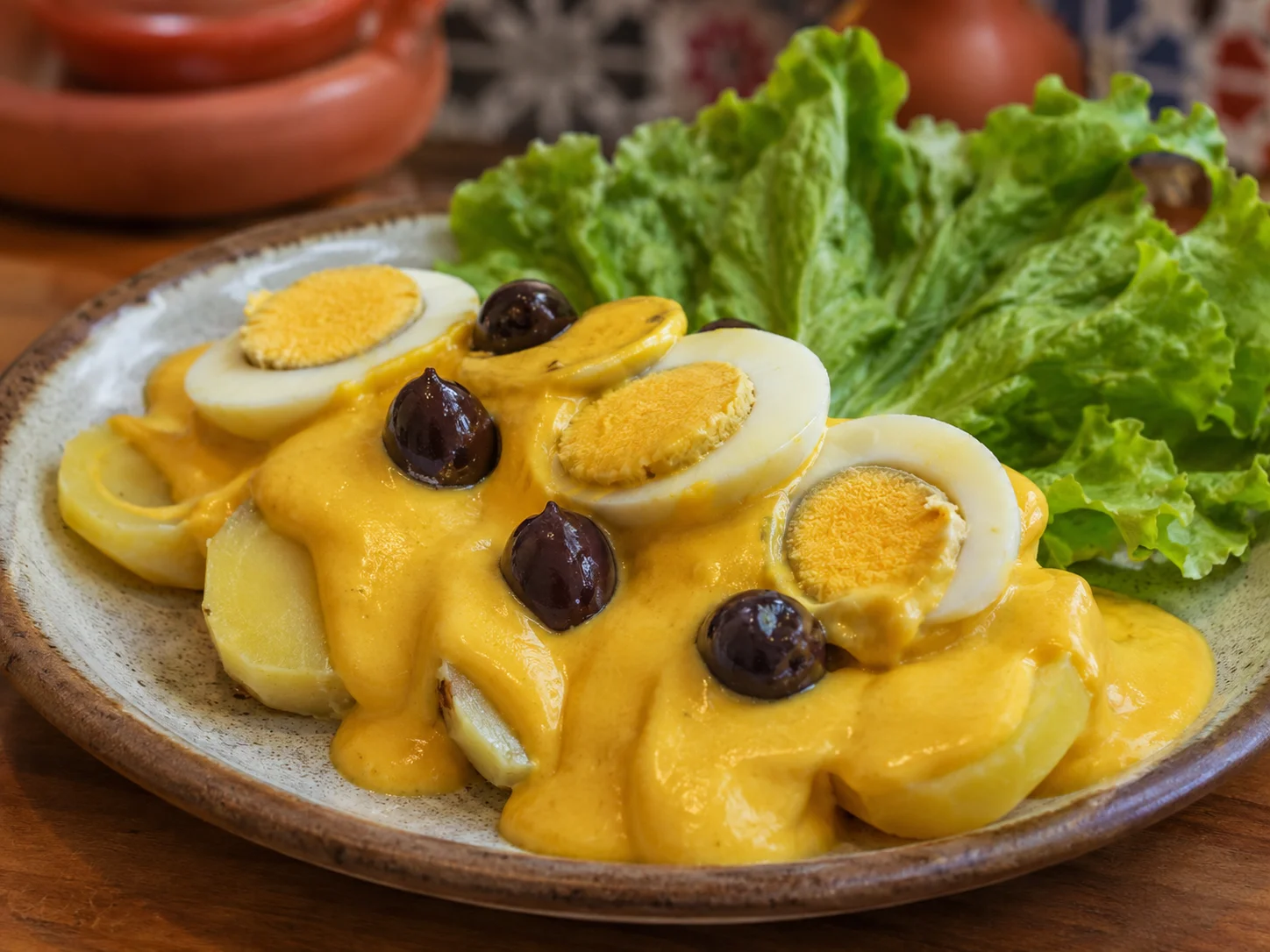 Papa a la huancaína con salsa amarilla, huevo y aceitunas